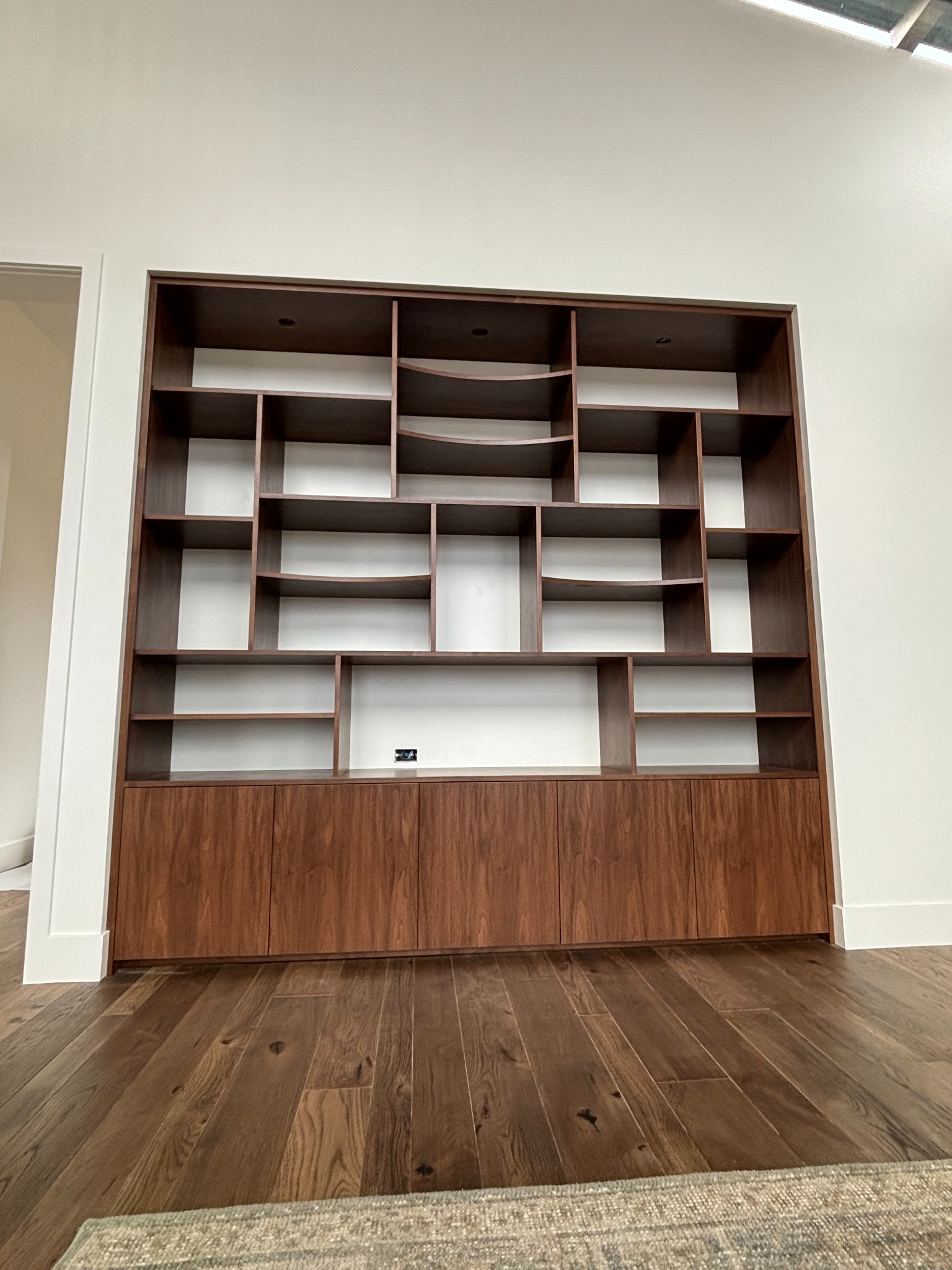 Floor-to-ceiling walnut built-in display shelving with lower cabinets